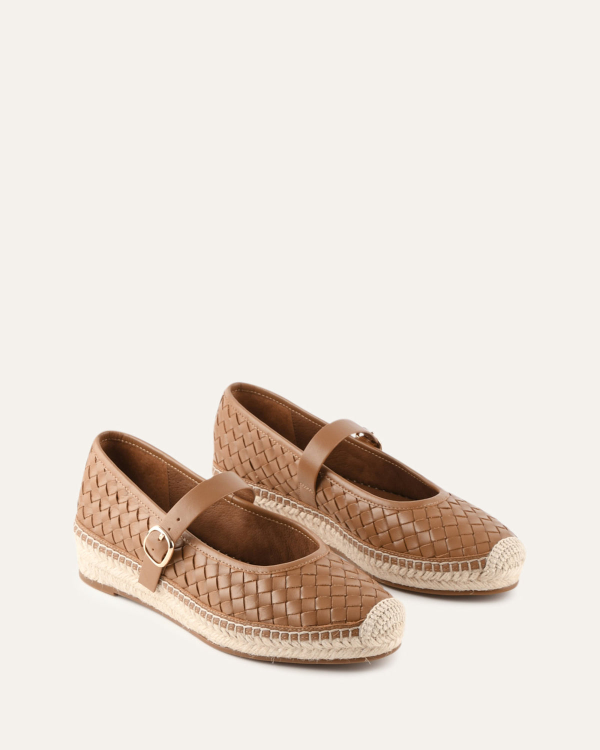 Pair of brown woven shoes with espadrille soles on a white background