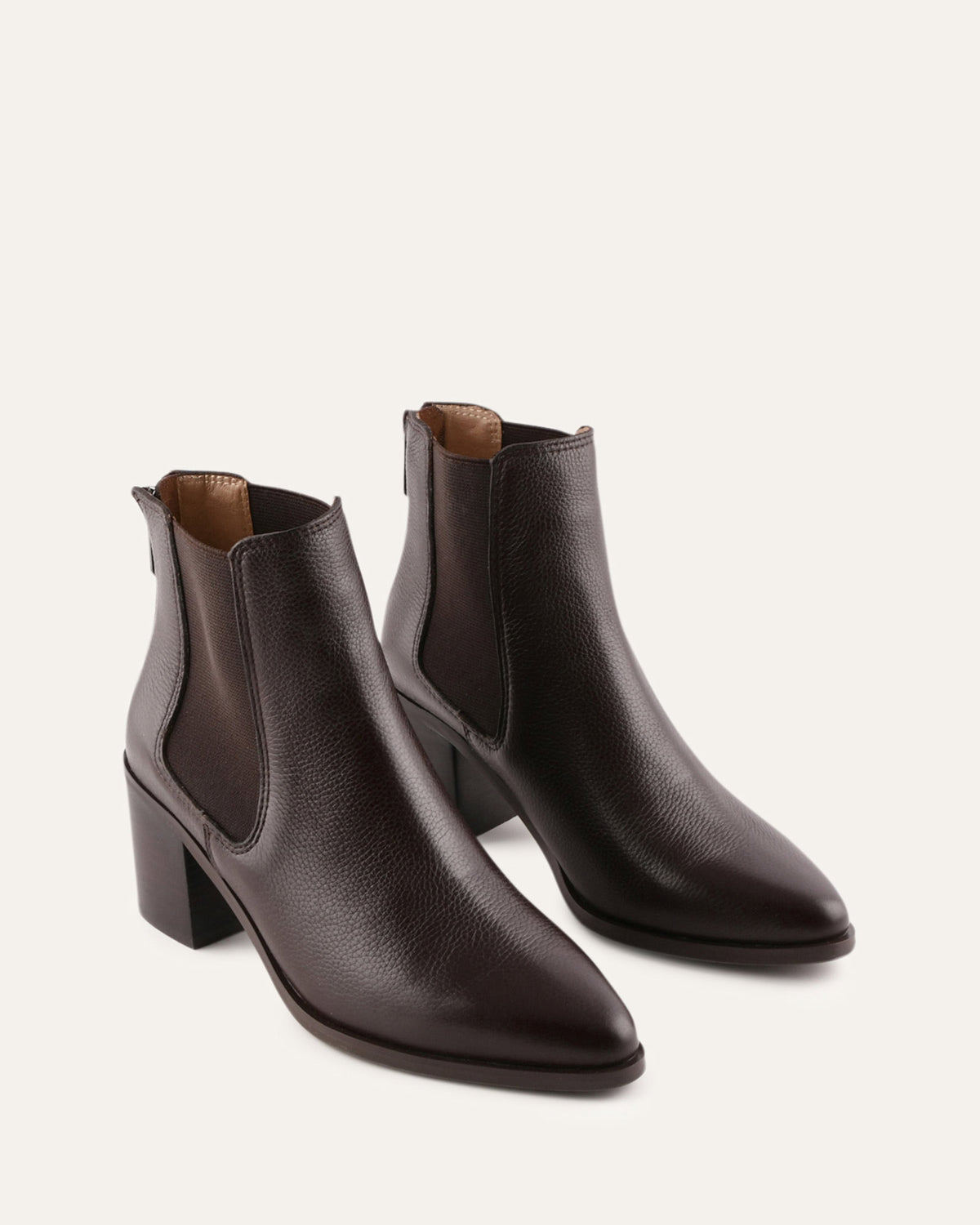 Pair of brown leather ankle boots on a light beige background