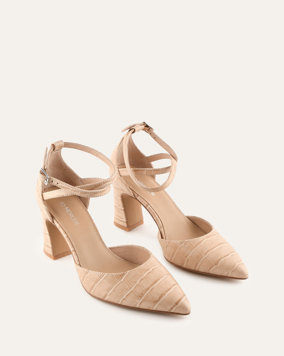 Beige high-heeled shoes with ankle straps on a light beige background