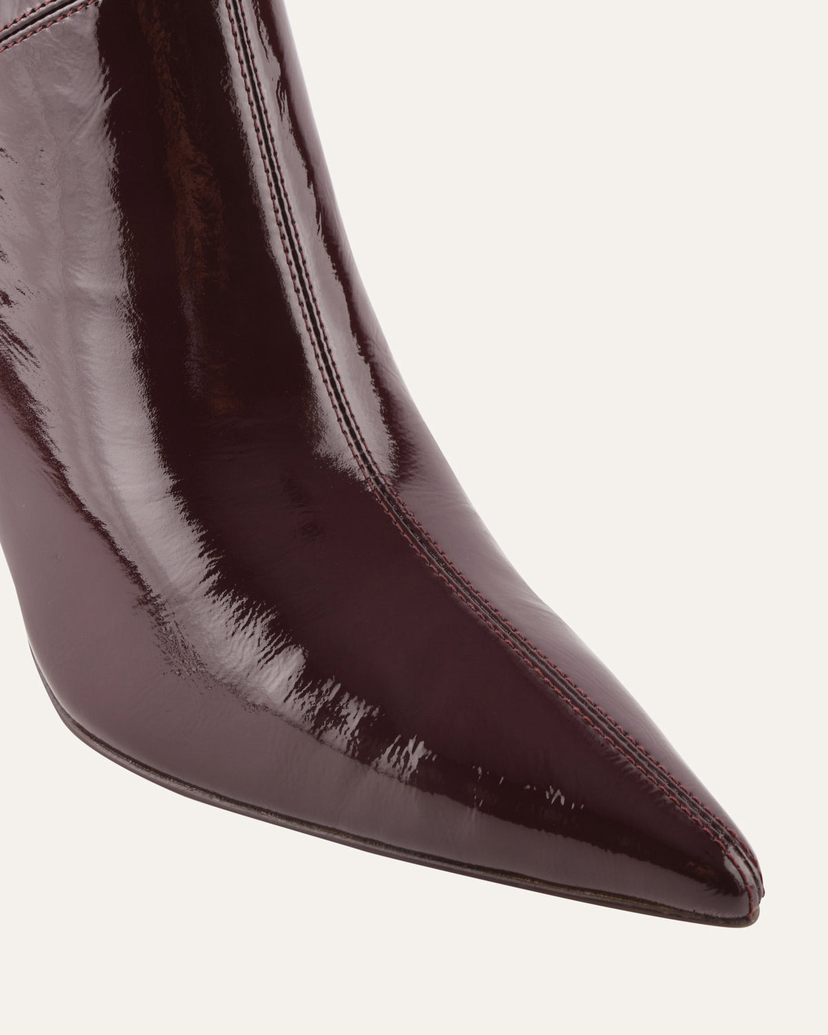 Close-up of a brown patent leather pointed-toe boot on a white background