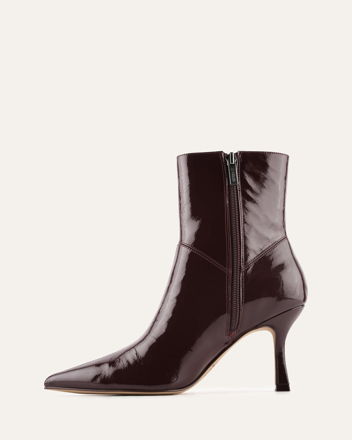 Black patent leather ankle boot on a light beige background