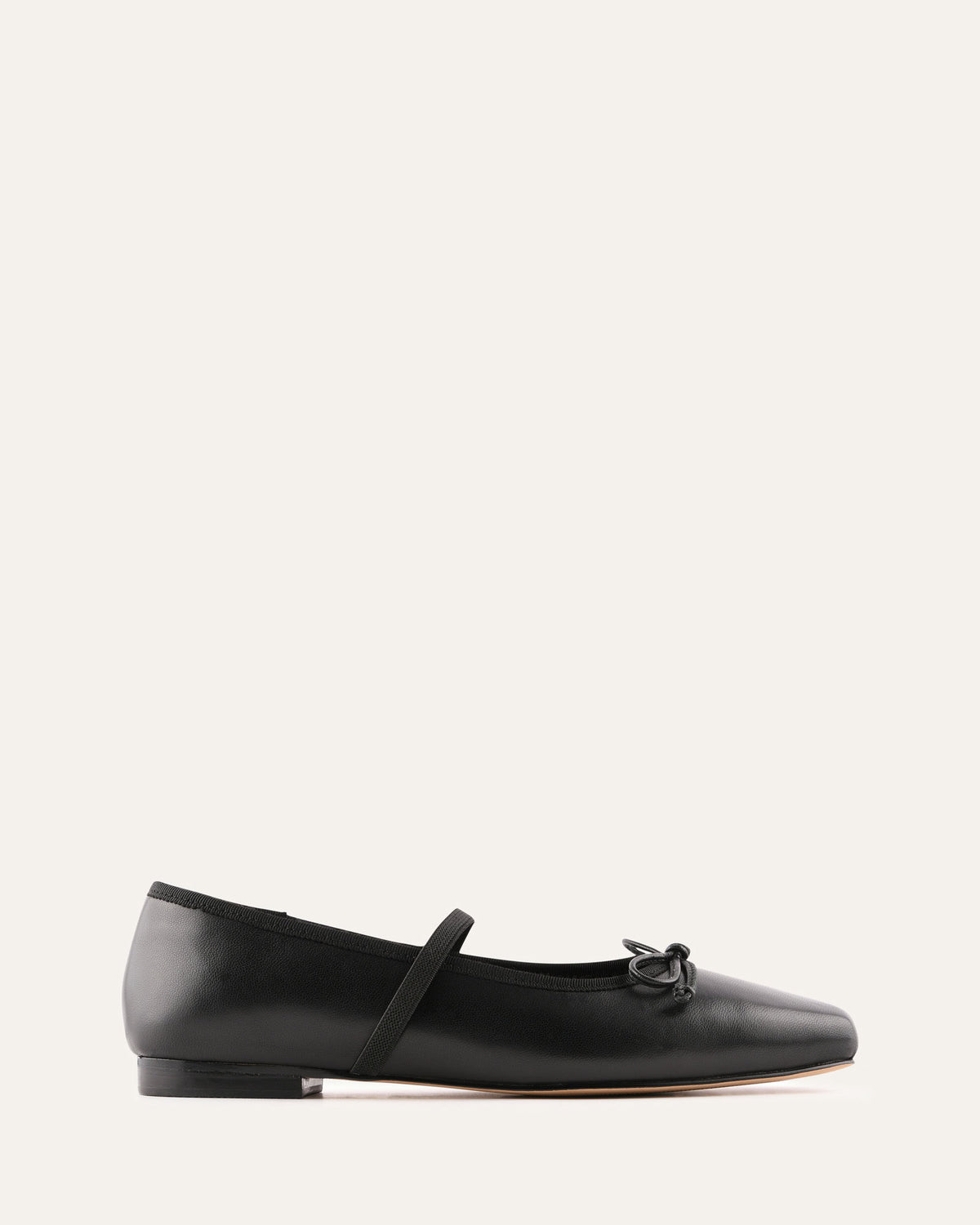 Black leather flat shoe with a strap on a white background