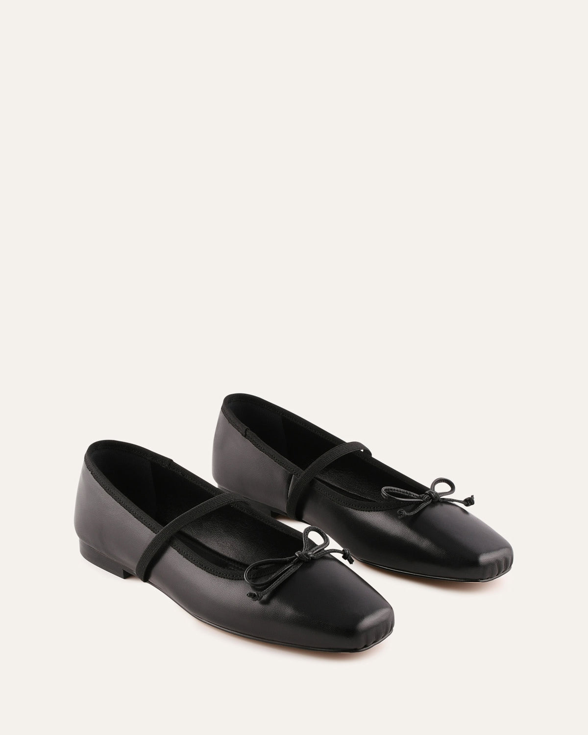 Pair of black ballet flats with bow details on a white background