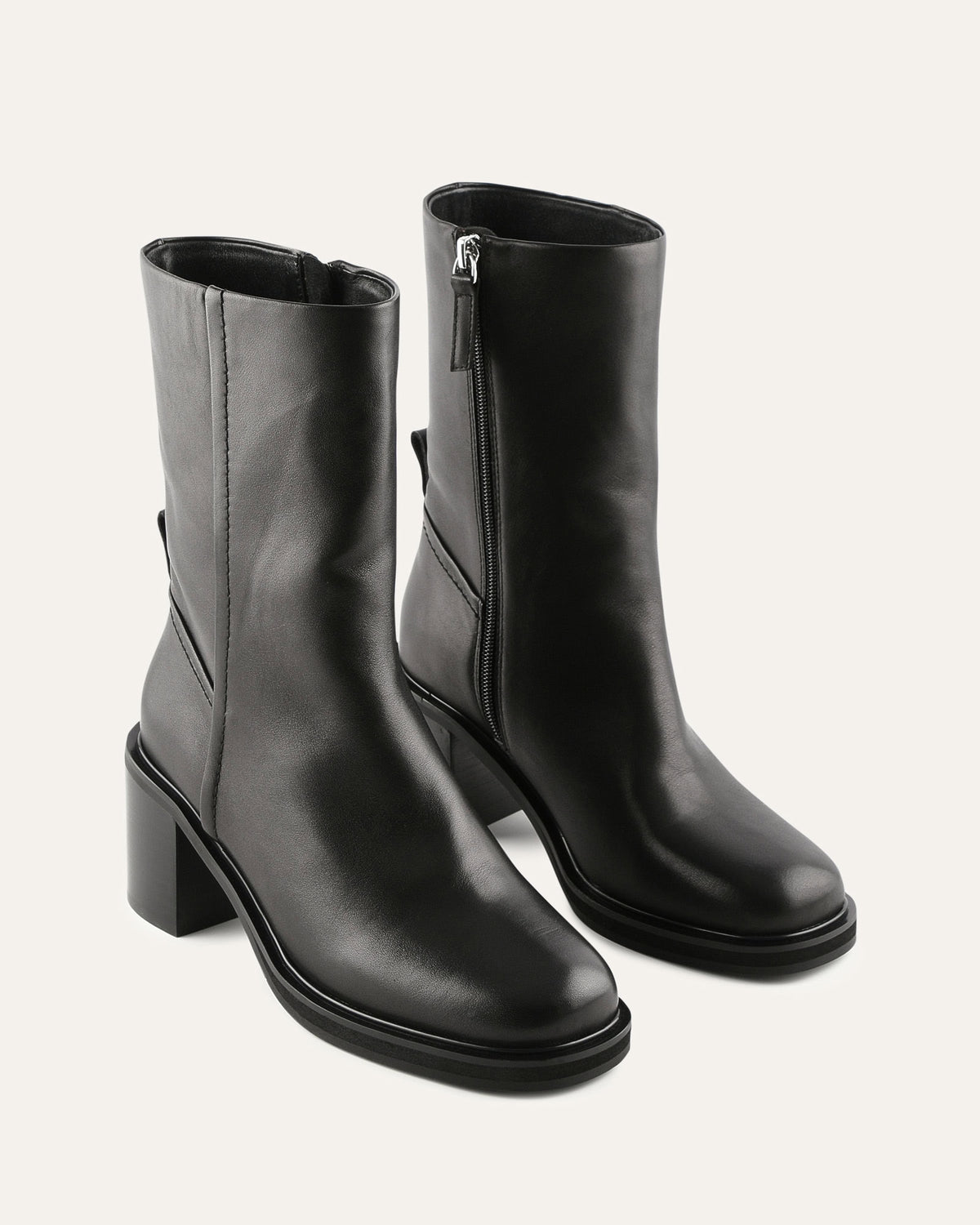 Pair of black leather boots with a zipper on a light gray background