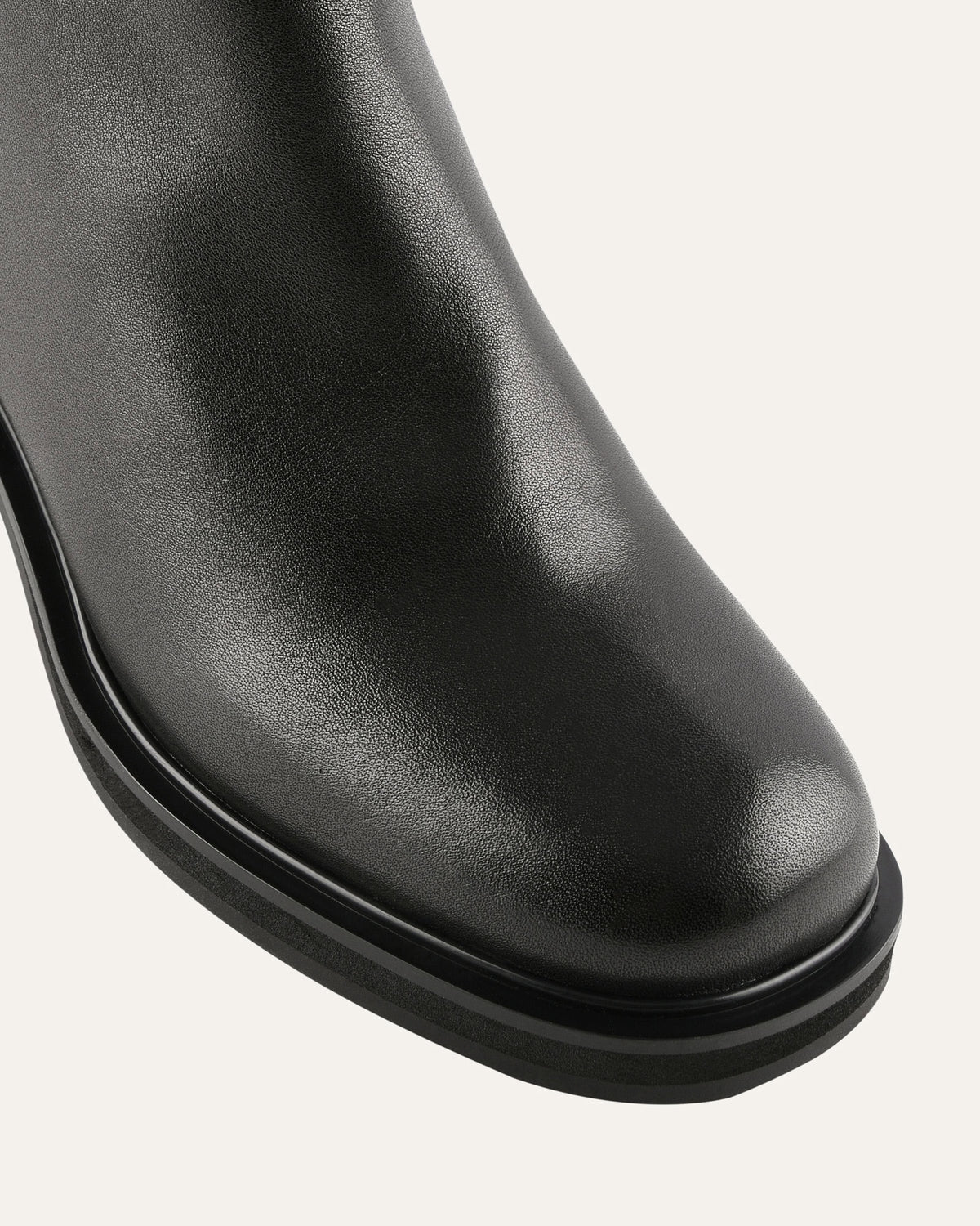 Close-up of a black leather boot on a light gray background