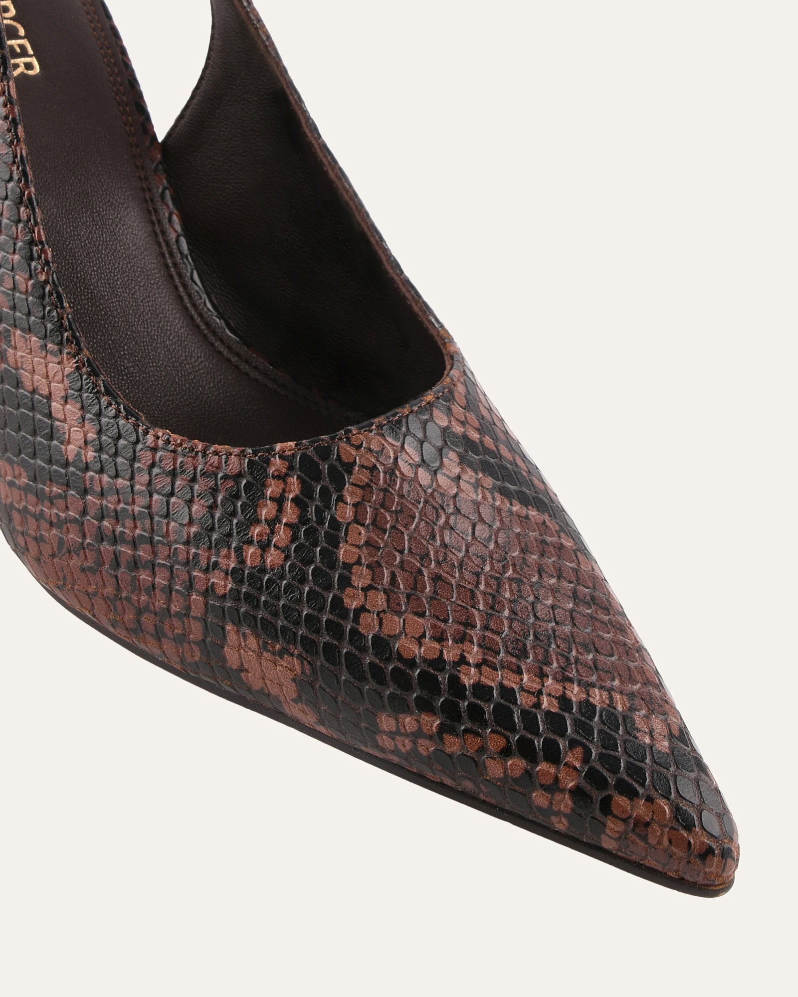 Brown high-heeled shoe with a slingback design on a light gray background