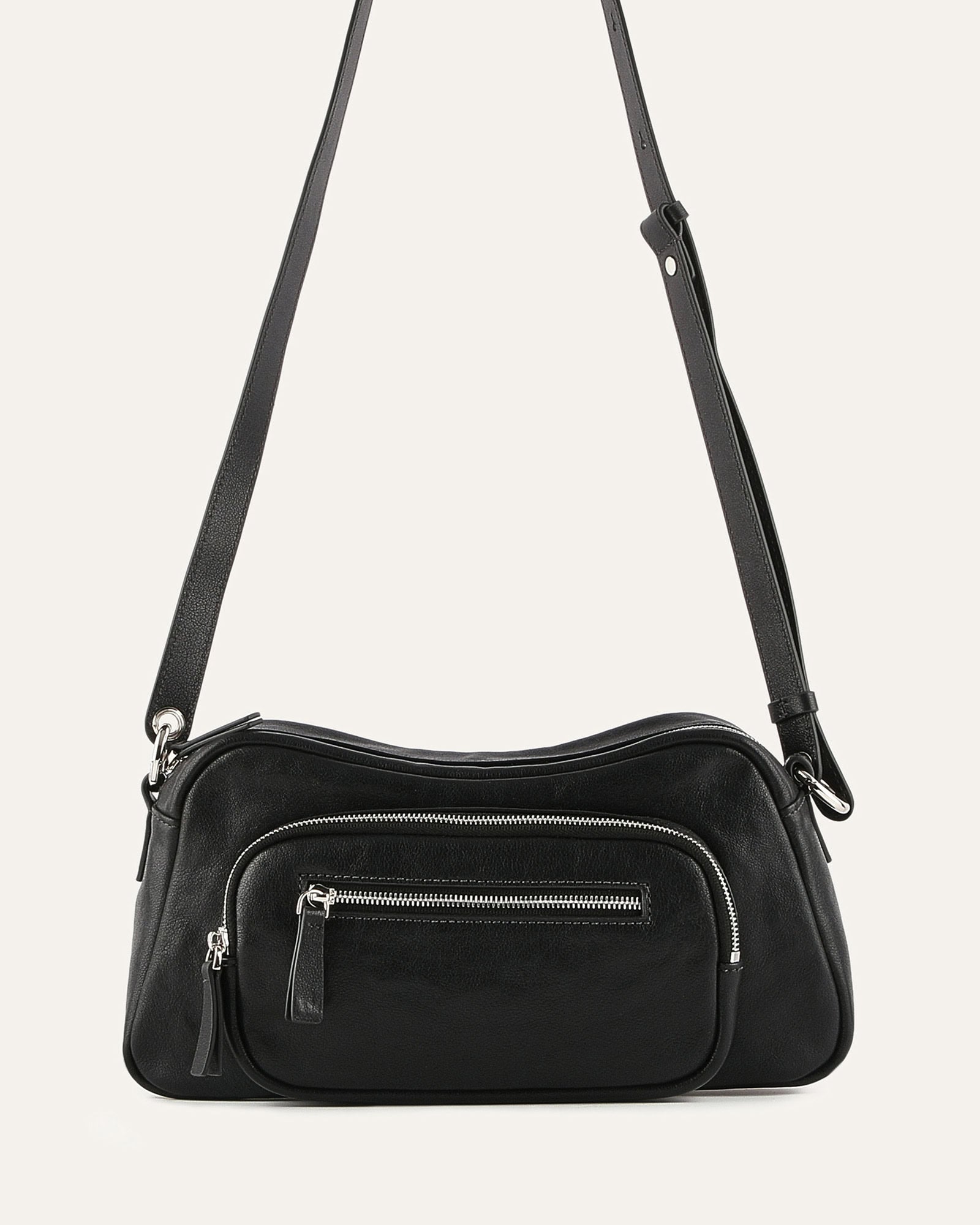 Black crossbody bag with zippers on a light gray background