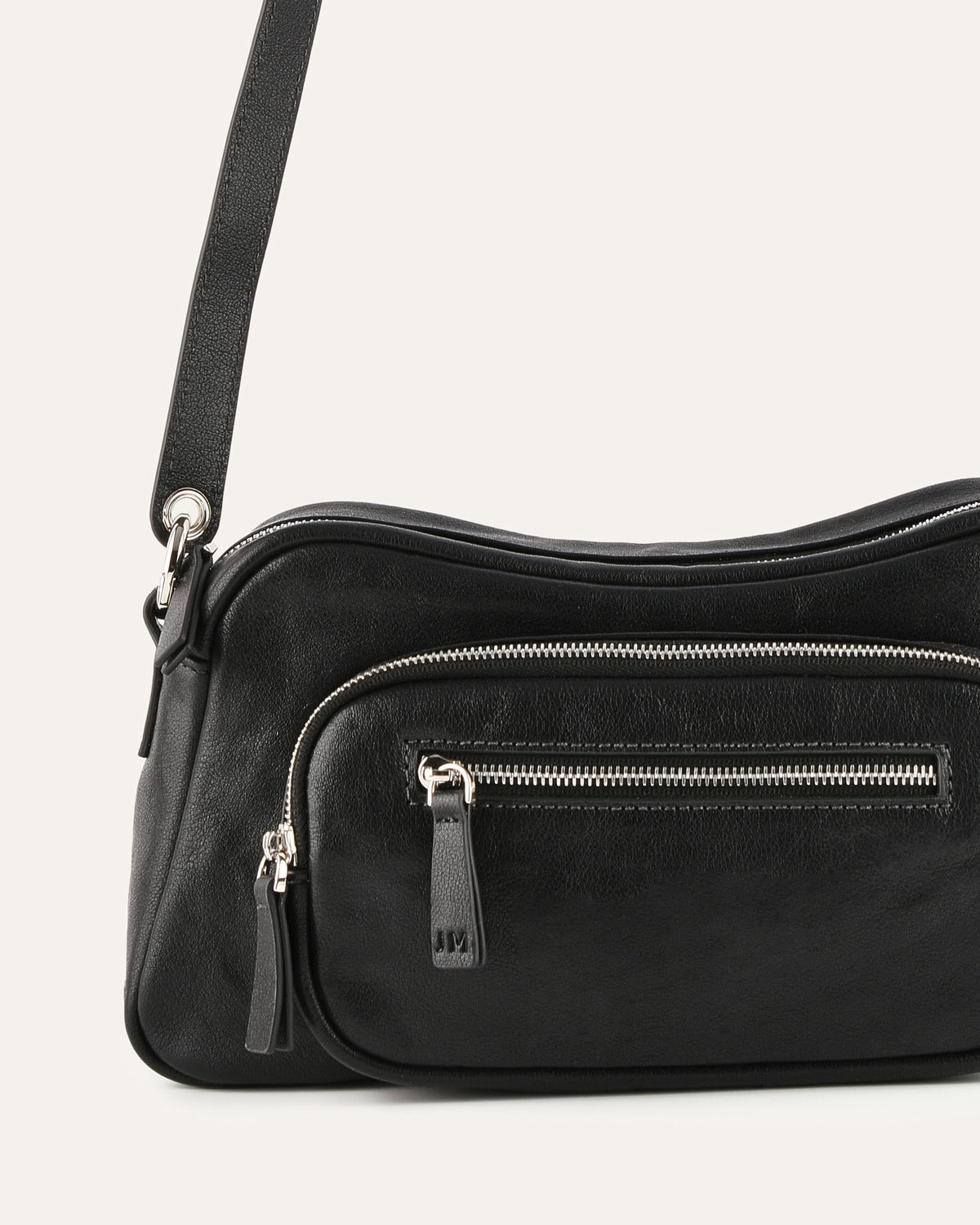 Black handbag with zippers on a light gray background