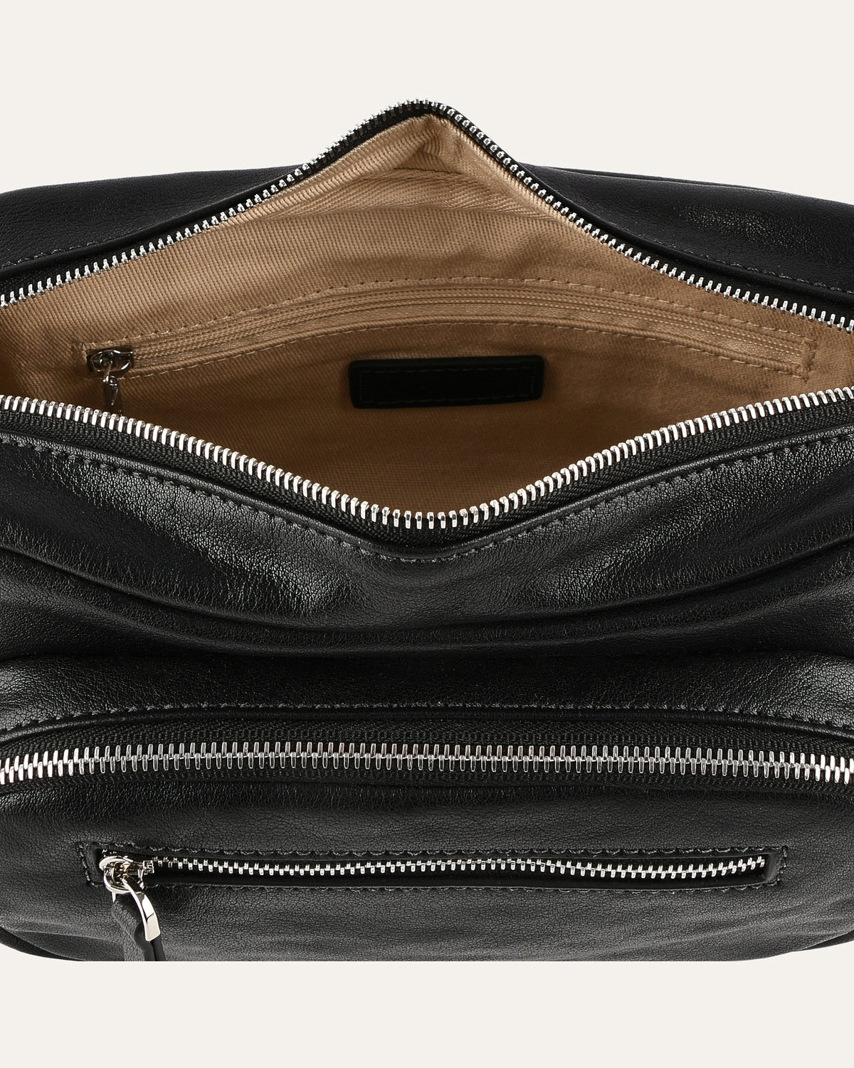 Close-up of a black leather bag with zippers on a white background