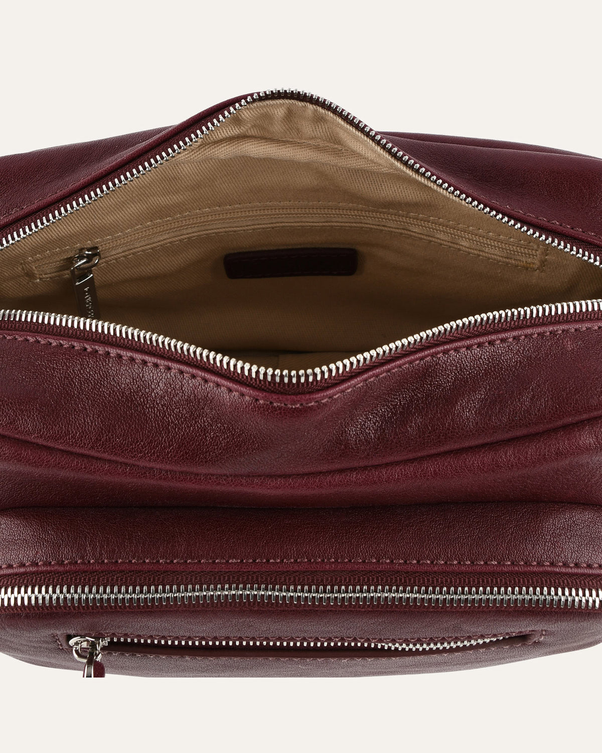 Close-up of a maroon leather bag with zippers on a white background