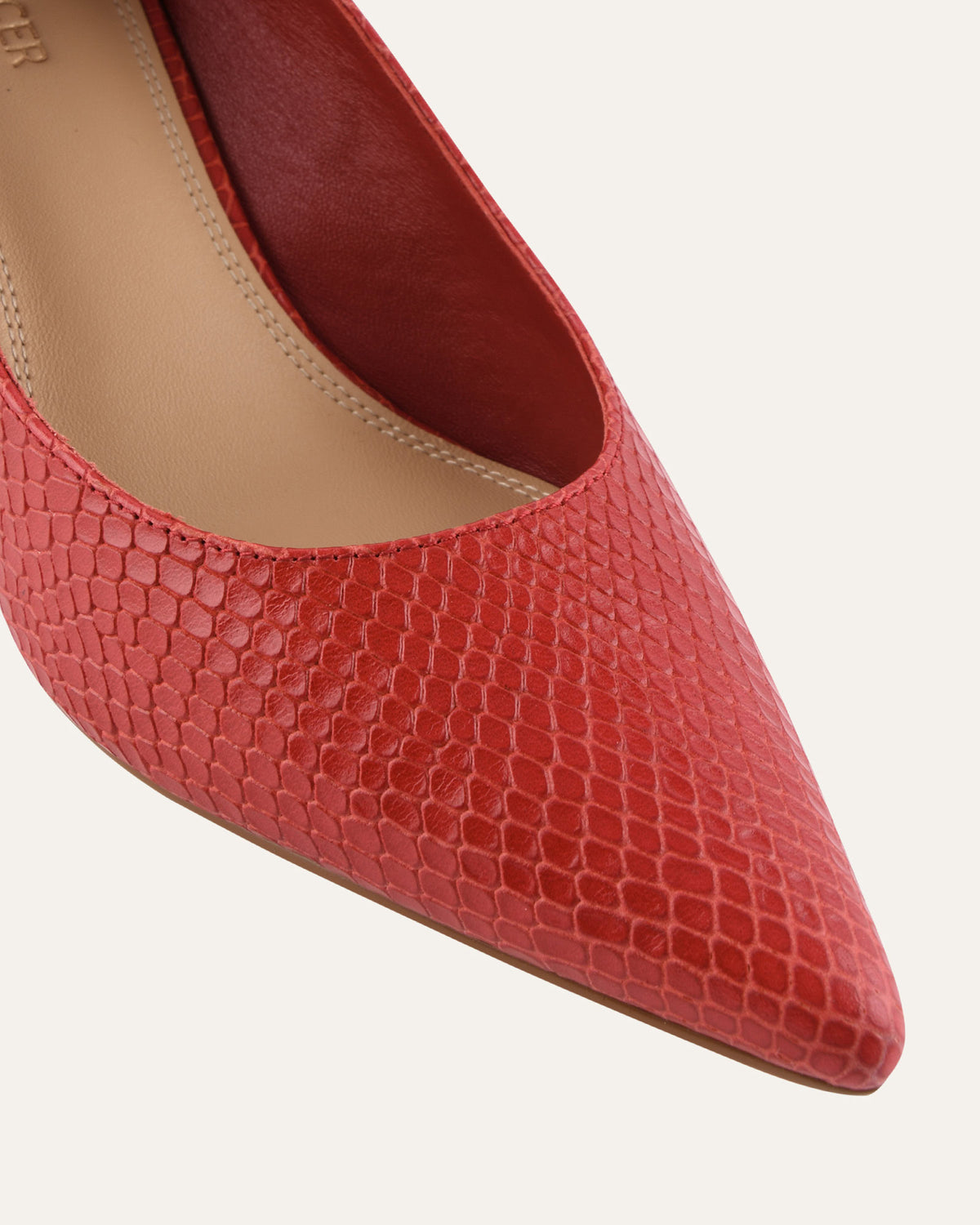 Red pointed-toe shoe with snake skin texture on a light gray background