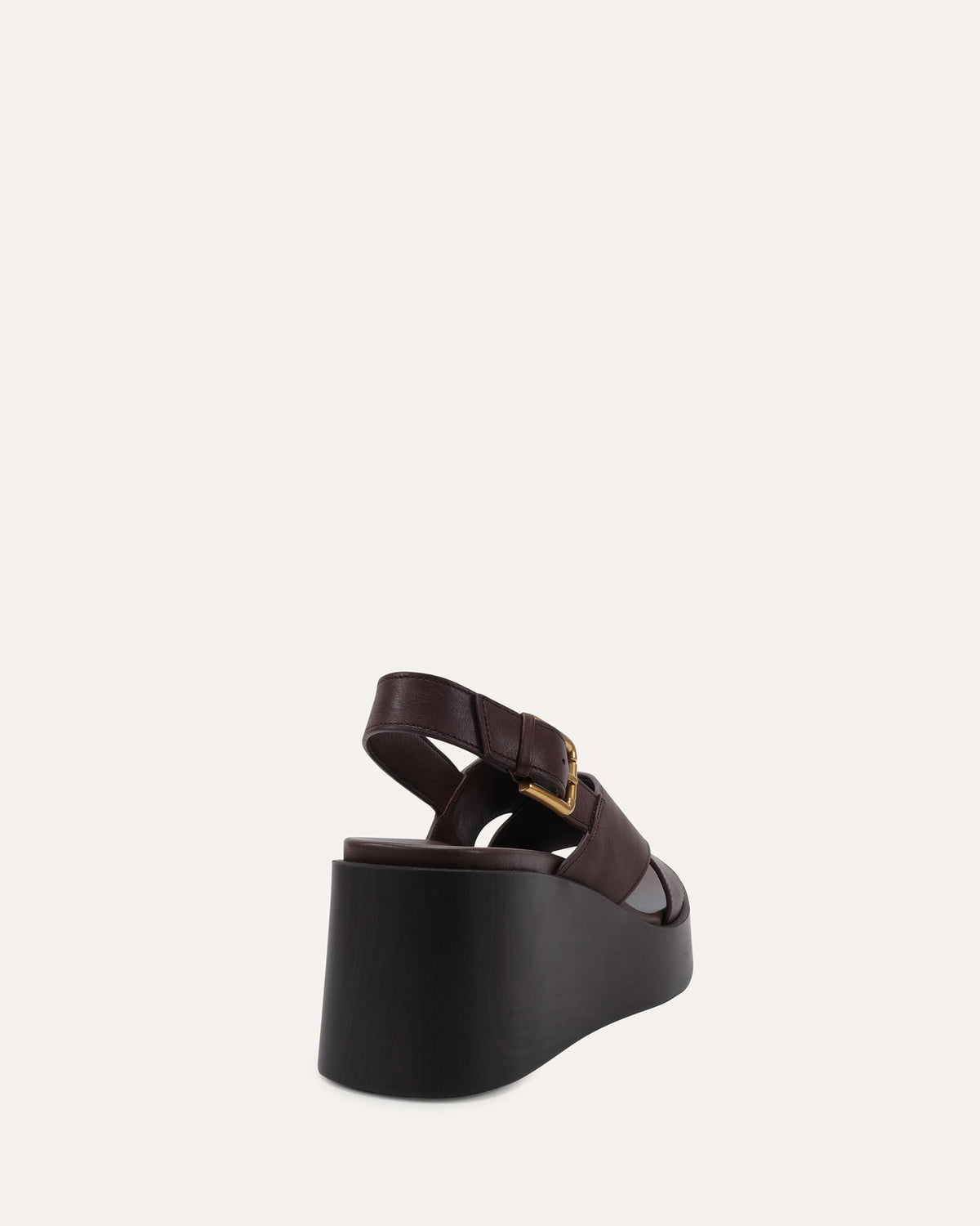 A single dark brown platform sandal with a chunky black wedge heel and a small gold buckle, shown from a rear three-quarter angle against a light off-white background.