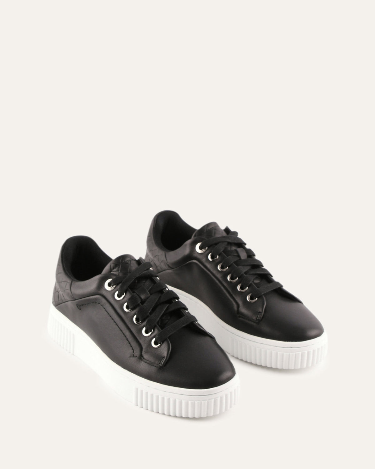 Black sneakers with white soles on a light gray background