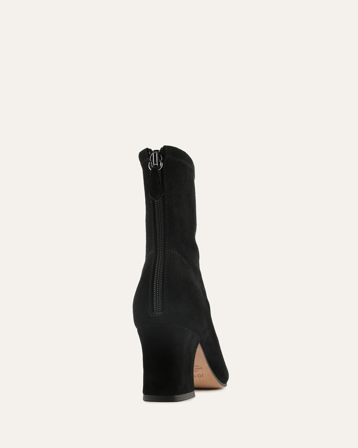 Black ankle boot with a zipper on a light beige background
