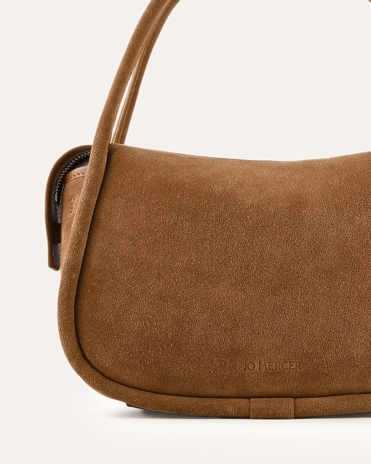 Brown suede handbag with a visible brand logo on a light background