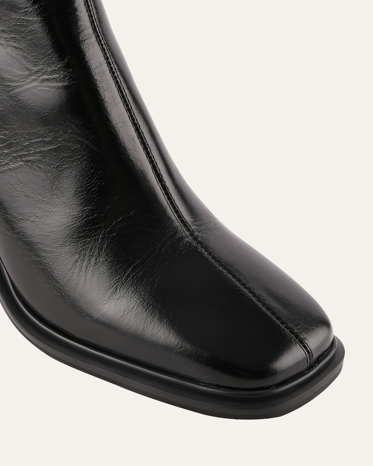 Close-up of a black leather boot on a light gray background