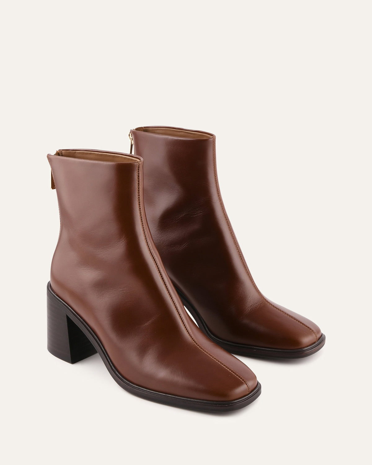 Pair of brown ankle boots on a light beige background