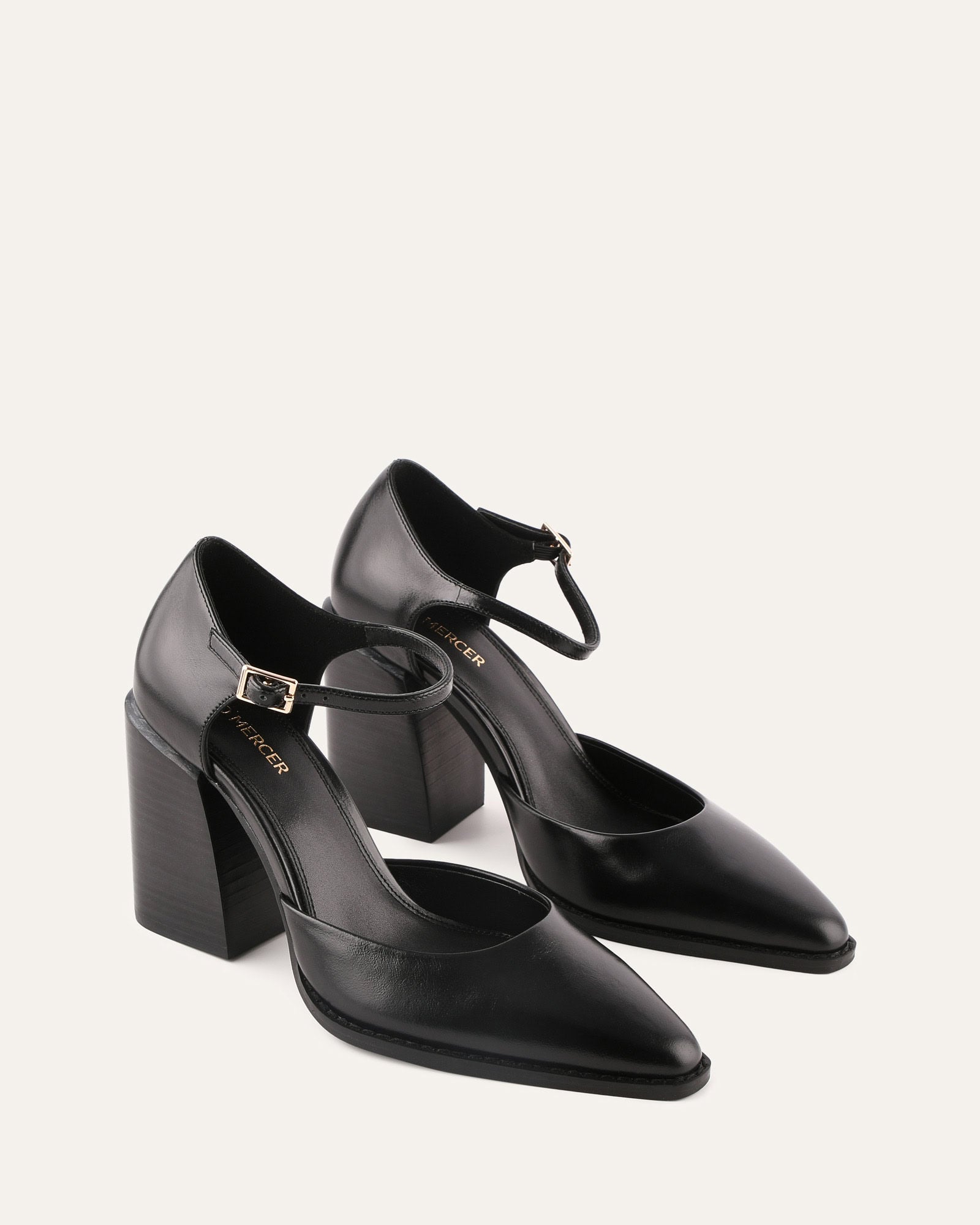 Black high-heeled shoe with a strap on a light gray background