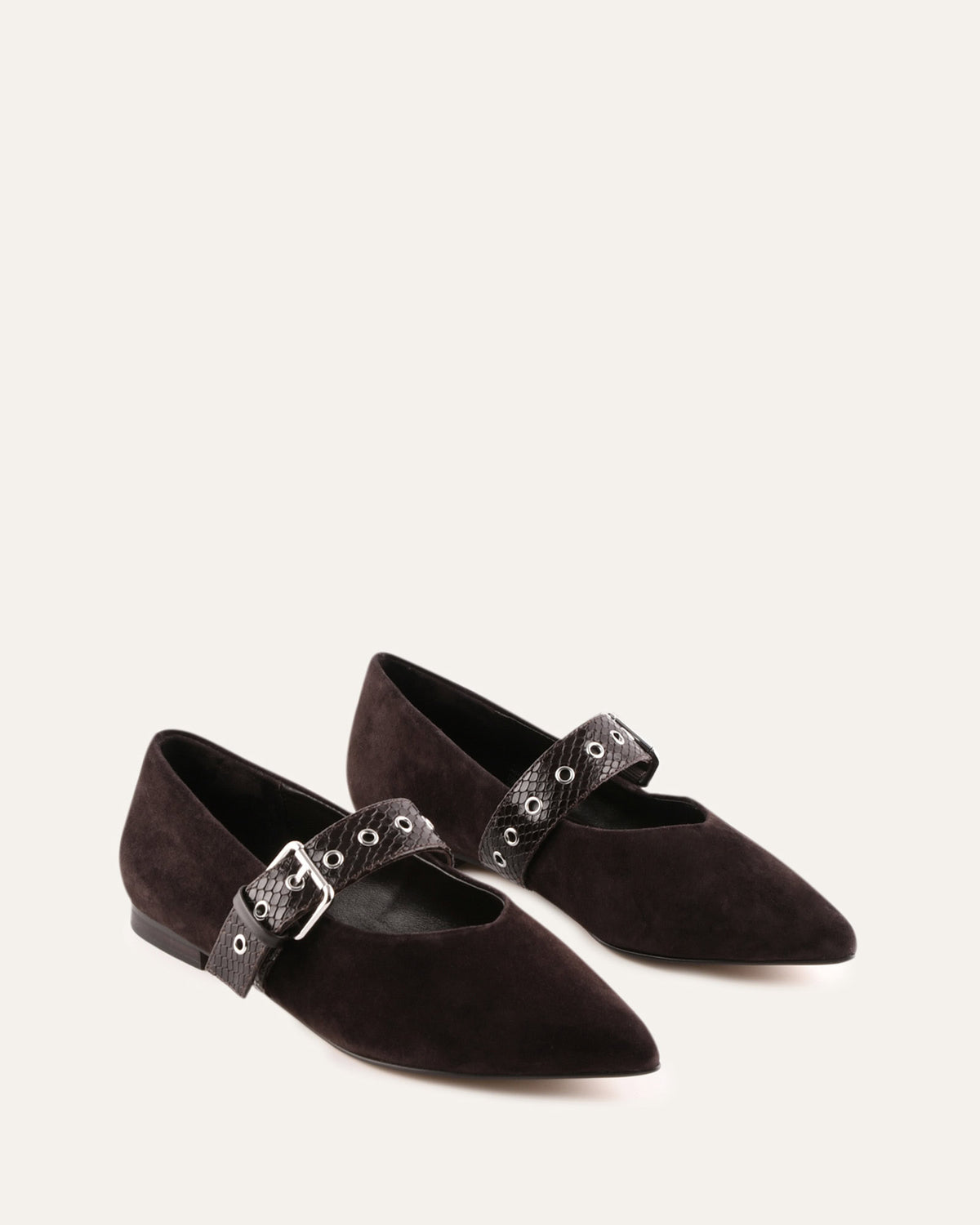 Pair of black pointed-toe flats with decorative straps on a light gray background