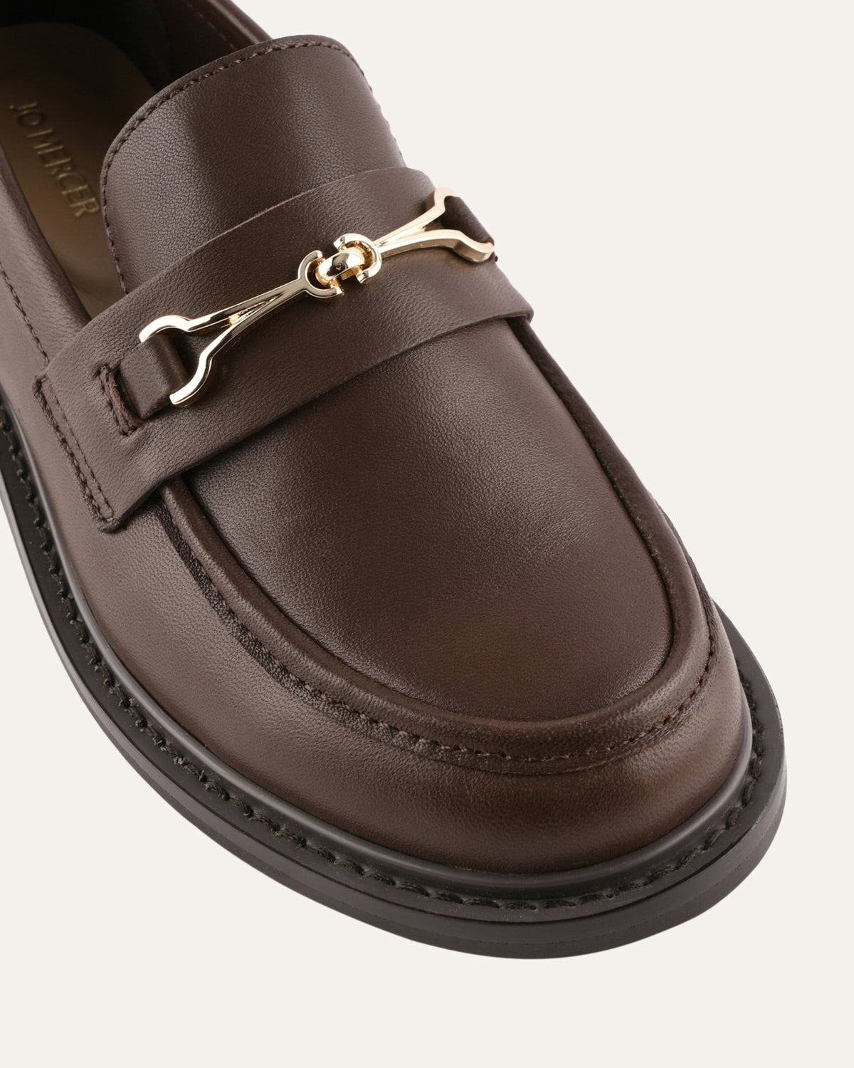 Brown leather loafer with gold buckle on a white background