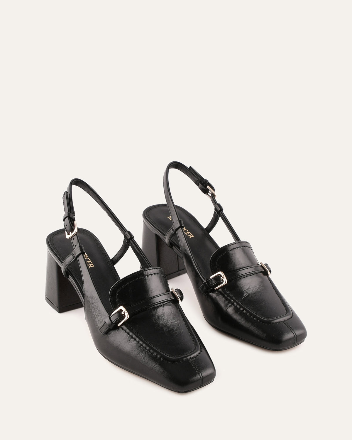 Pair of black high-heeled shoes with buckles on a light gray background