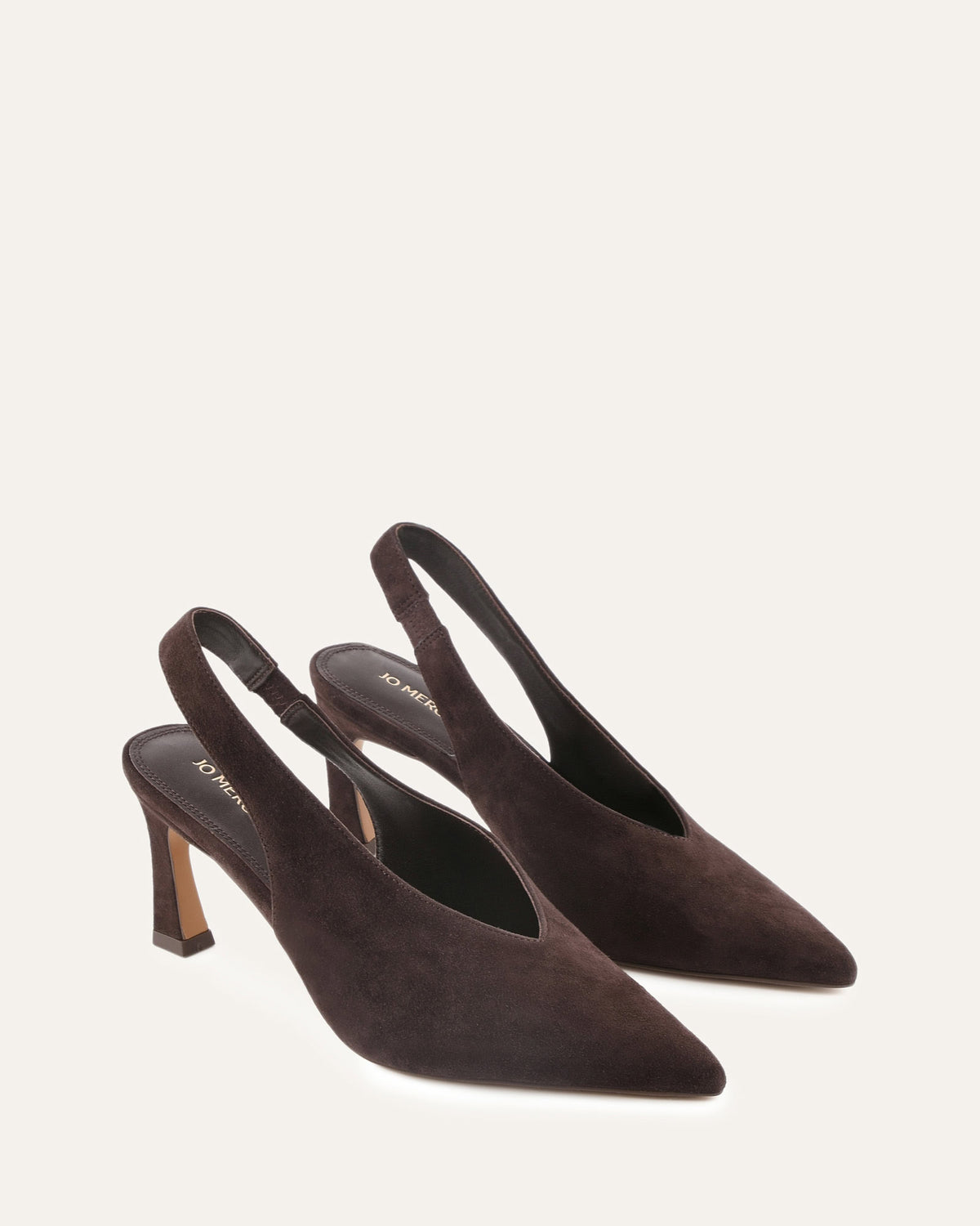Pair of brown suede slingback heels on a light beige background
