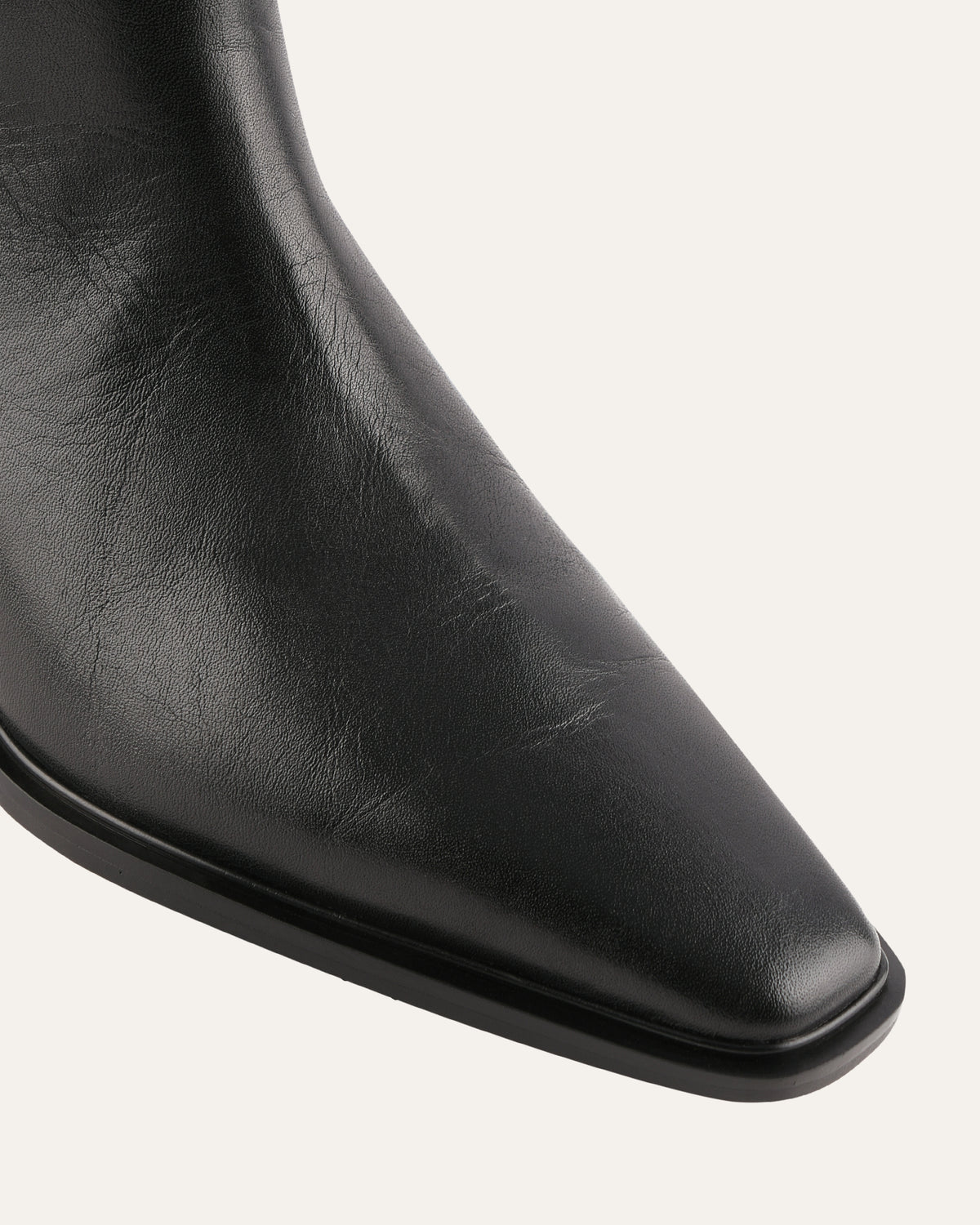 Close-up of a black leather boot on a light gray background
