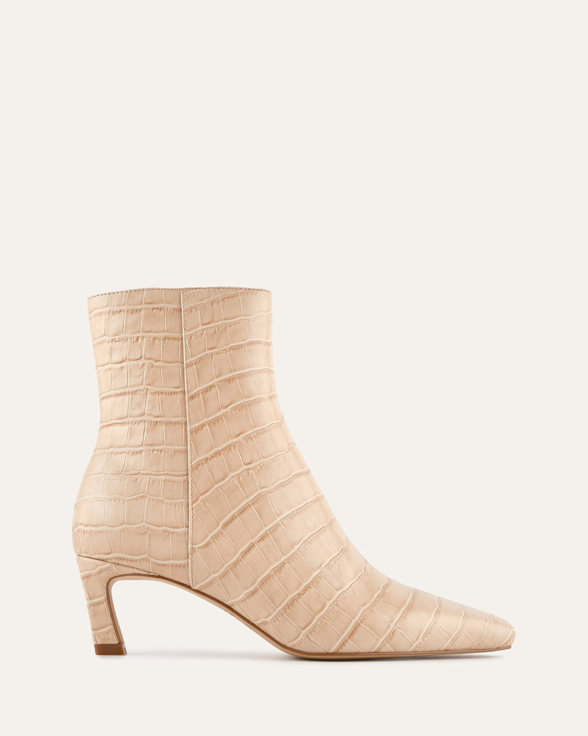 Beige ankle boot with crocodile texture on a light beige background