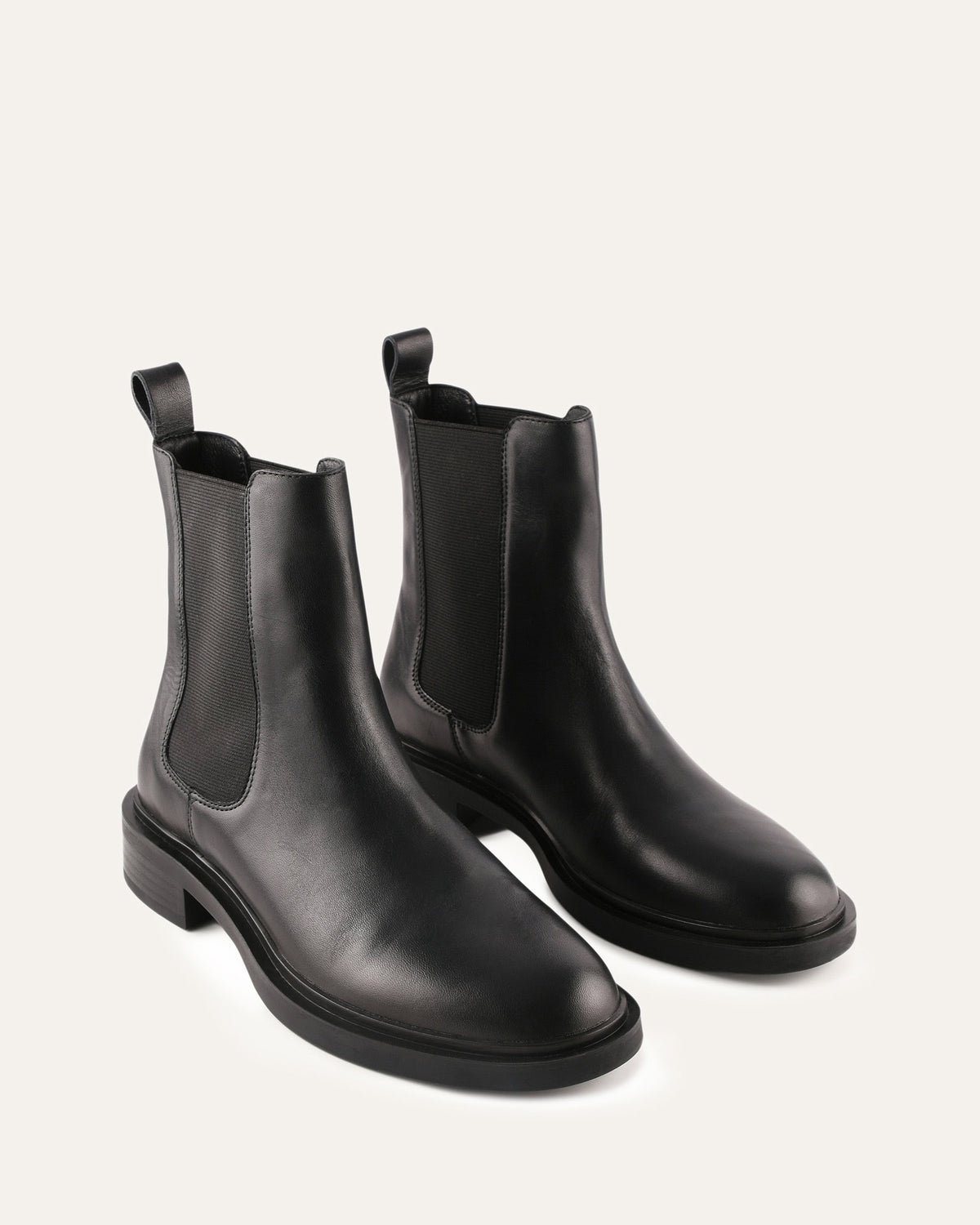 Pair of black leather Chelsea boots on a light gray background