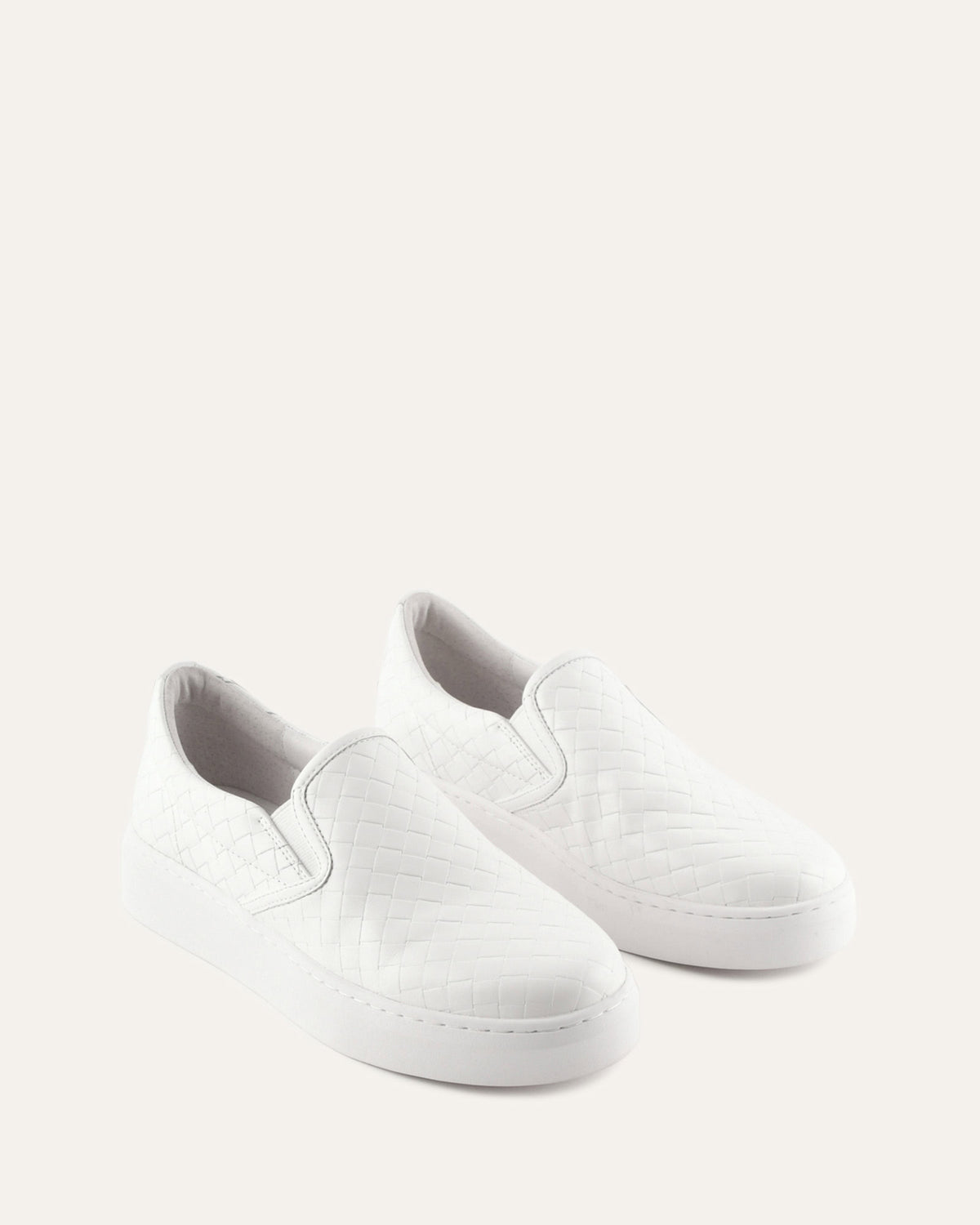 White slip-on sneakers on a light gray background