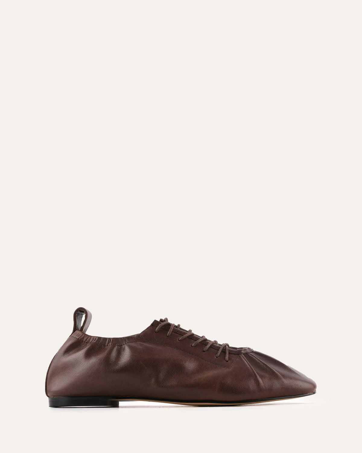 Brown leather shoe on a light beige background