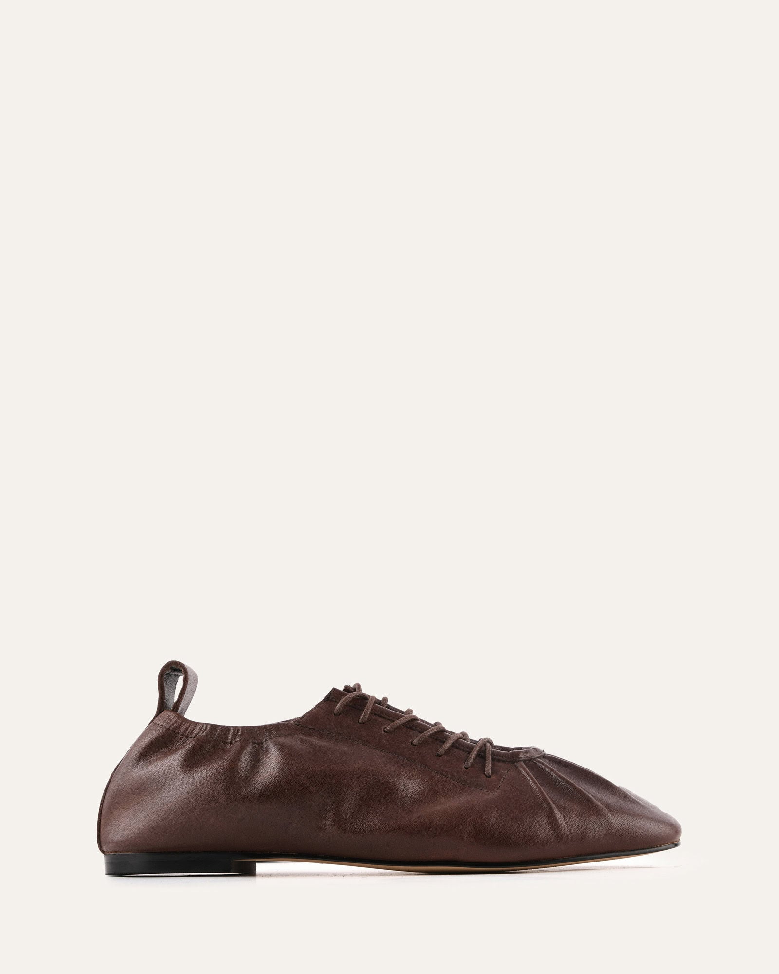 Brown leather shoe on a light beige background