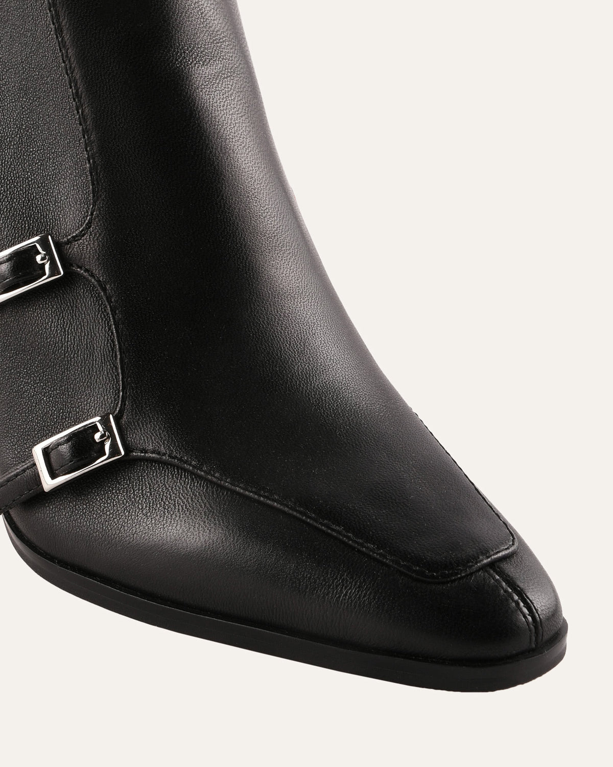 Black leather boot with a buckle on a white background