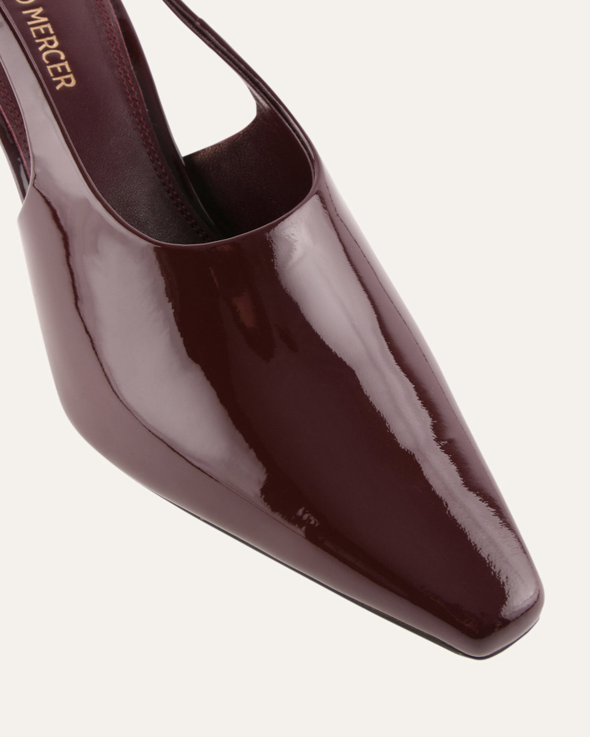 Shiny brown high-heeled shoe on a light gray background