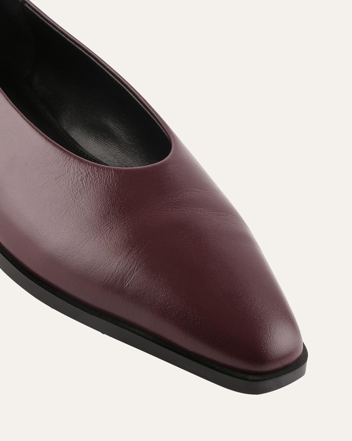 Maroon leather flat shoe on a light gray background