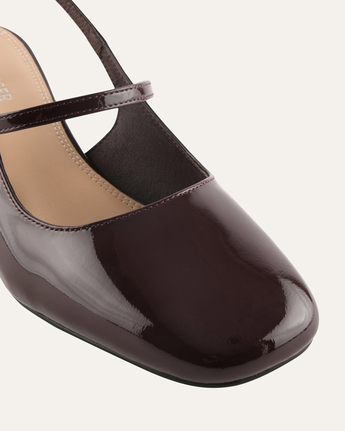Brown patent leather shoe with a strap on a white background
