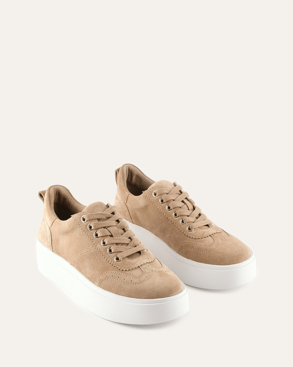 Pair of tan sneakers with white soles on a light beige background