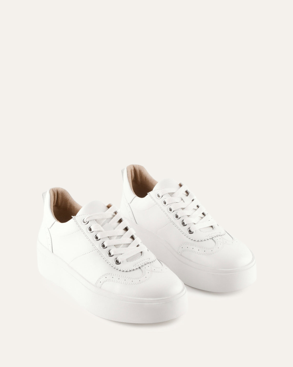 Pair of white sneakers on a light beige background