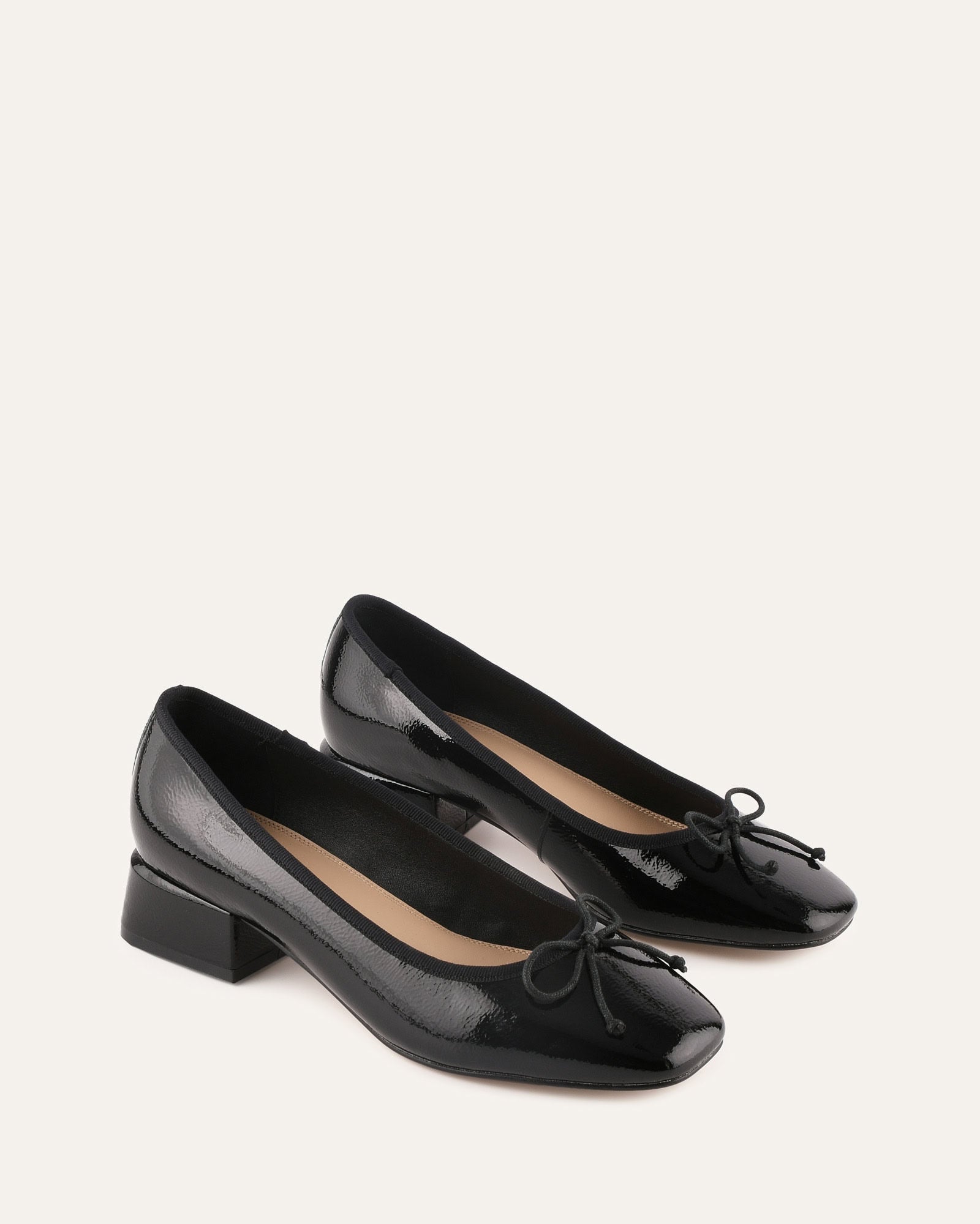 Black patent leather shoe with a bow on a white background