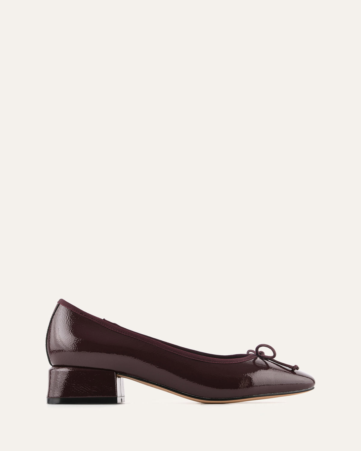 Brown patent leather shoe with a bow on a light gray background