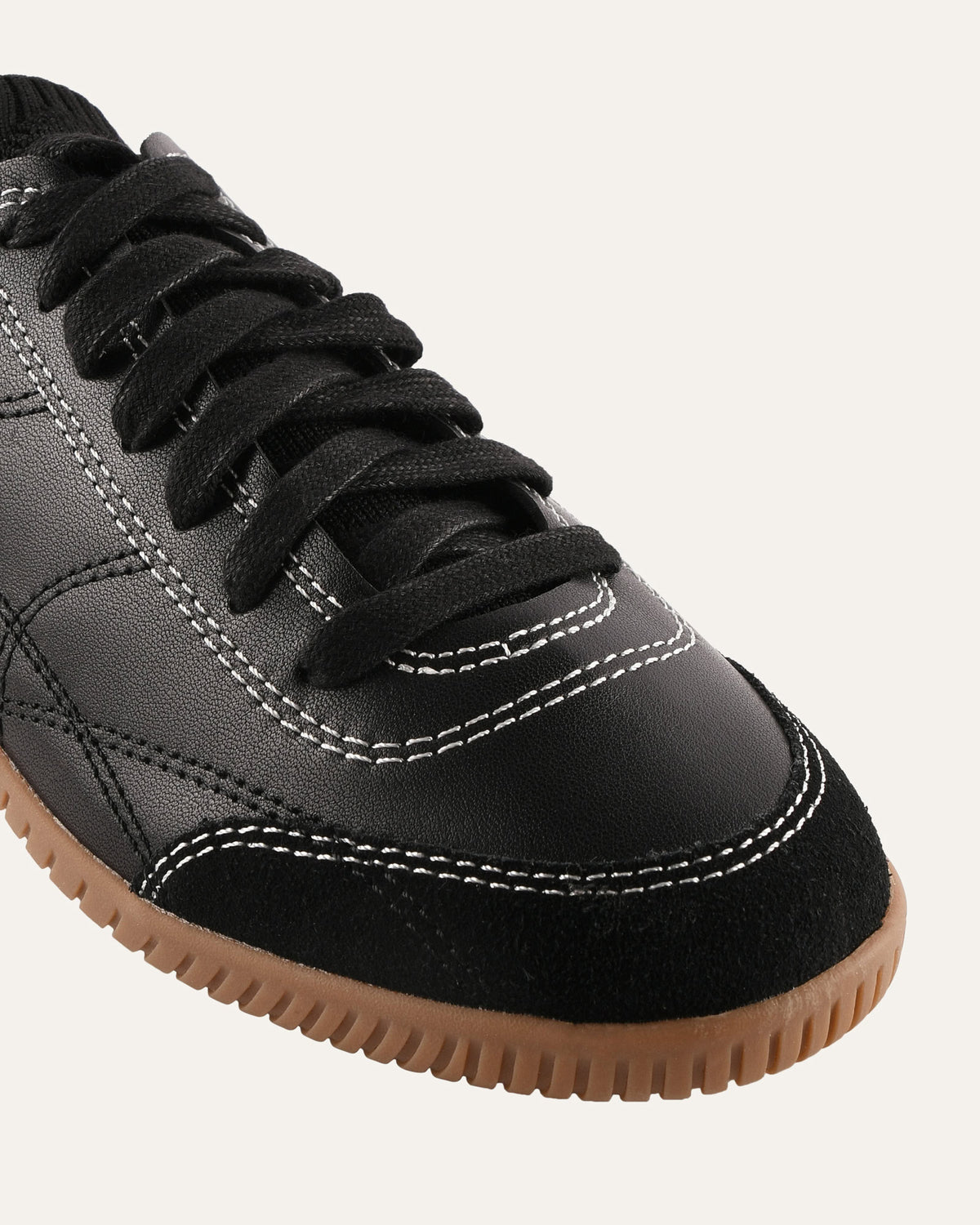 Gray sneaker with black laces and brown sole on a light gray background