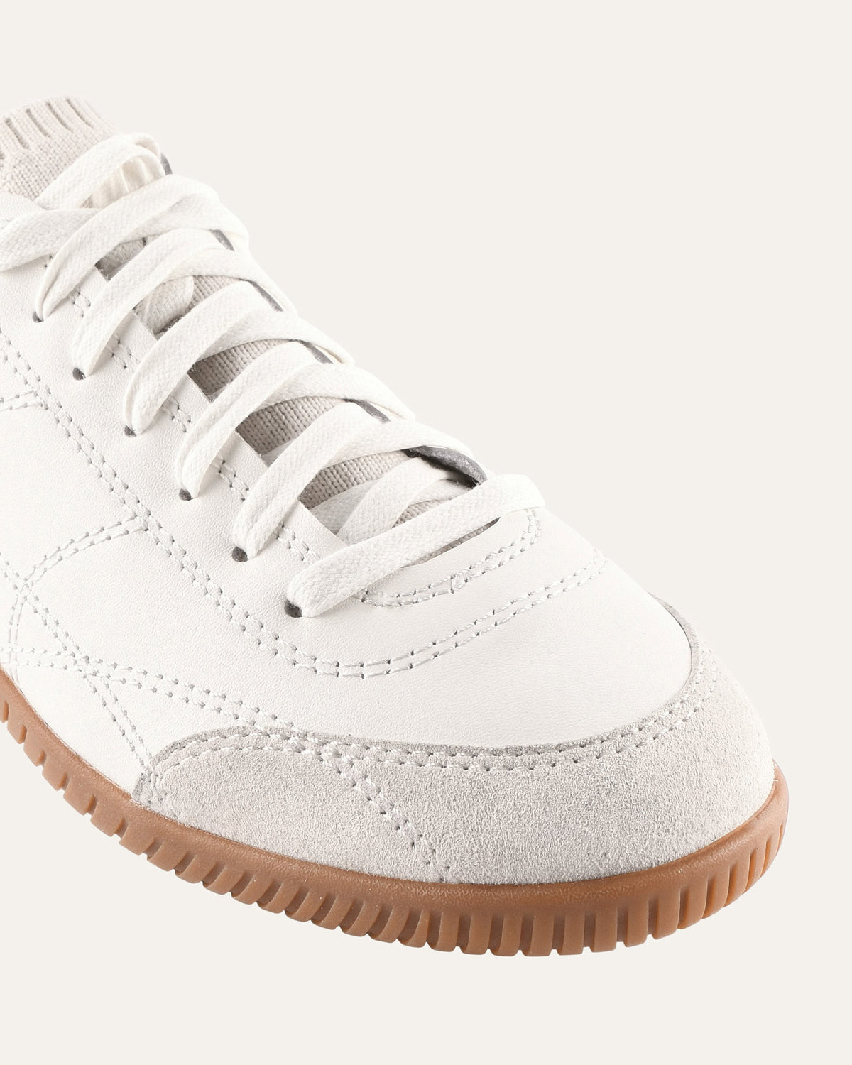 White sneaker with brown sole on a light gray background