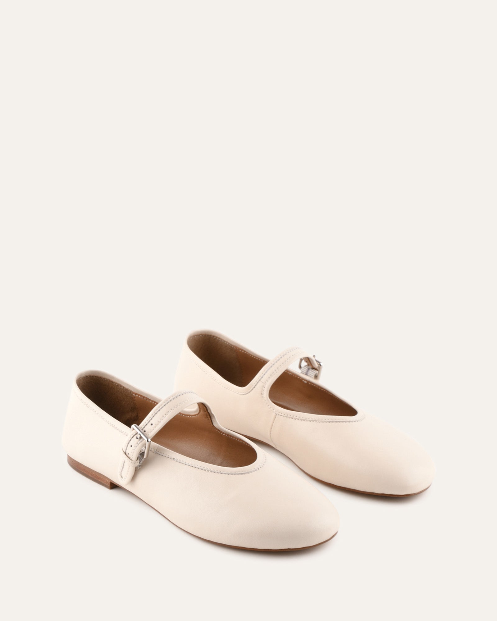 White flat shoe with a strap on a light gray background