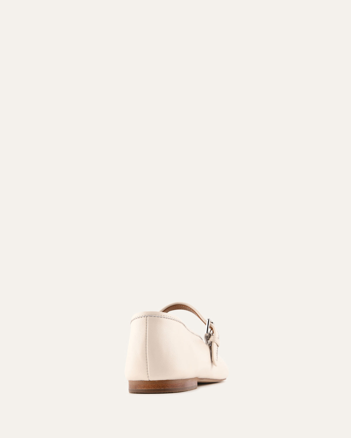 White sandal with brown sole on a light beige background