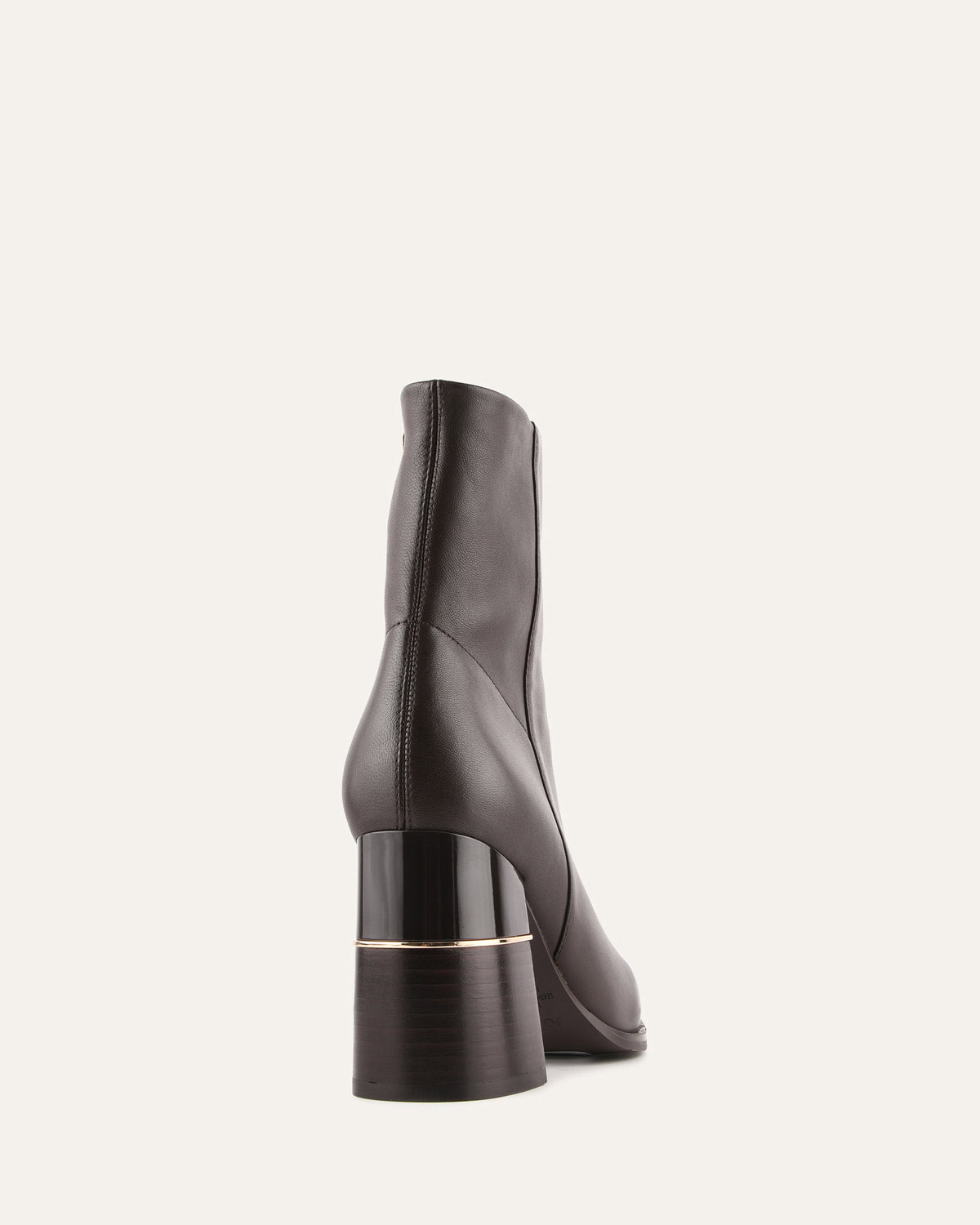 Black ankle boot with a gold accent on a light gray background