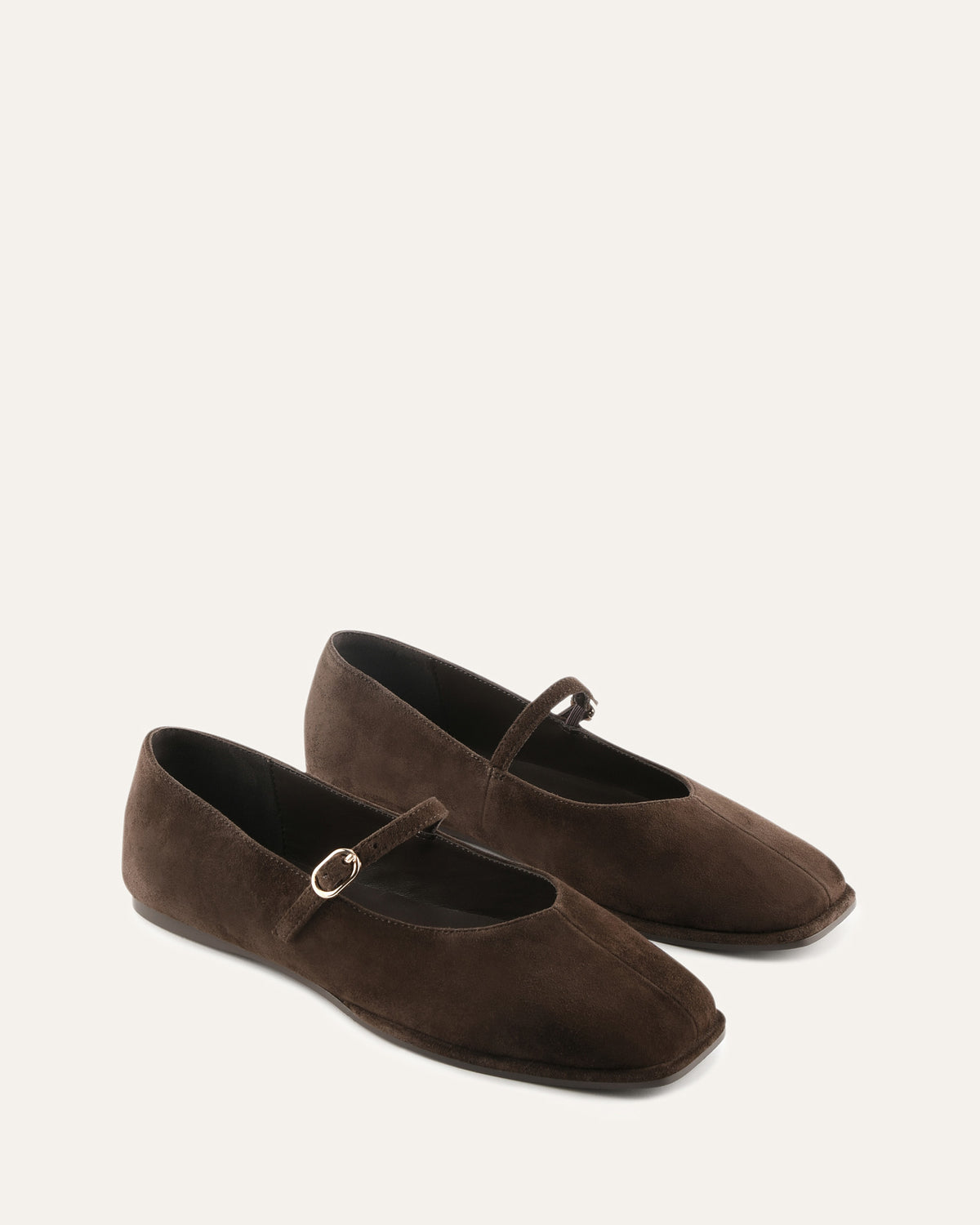 Pair of brown suede shoes with a strap on a white background