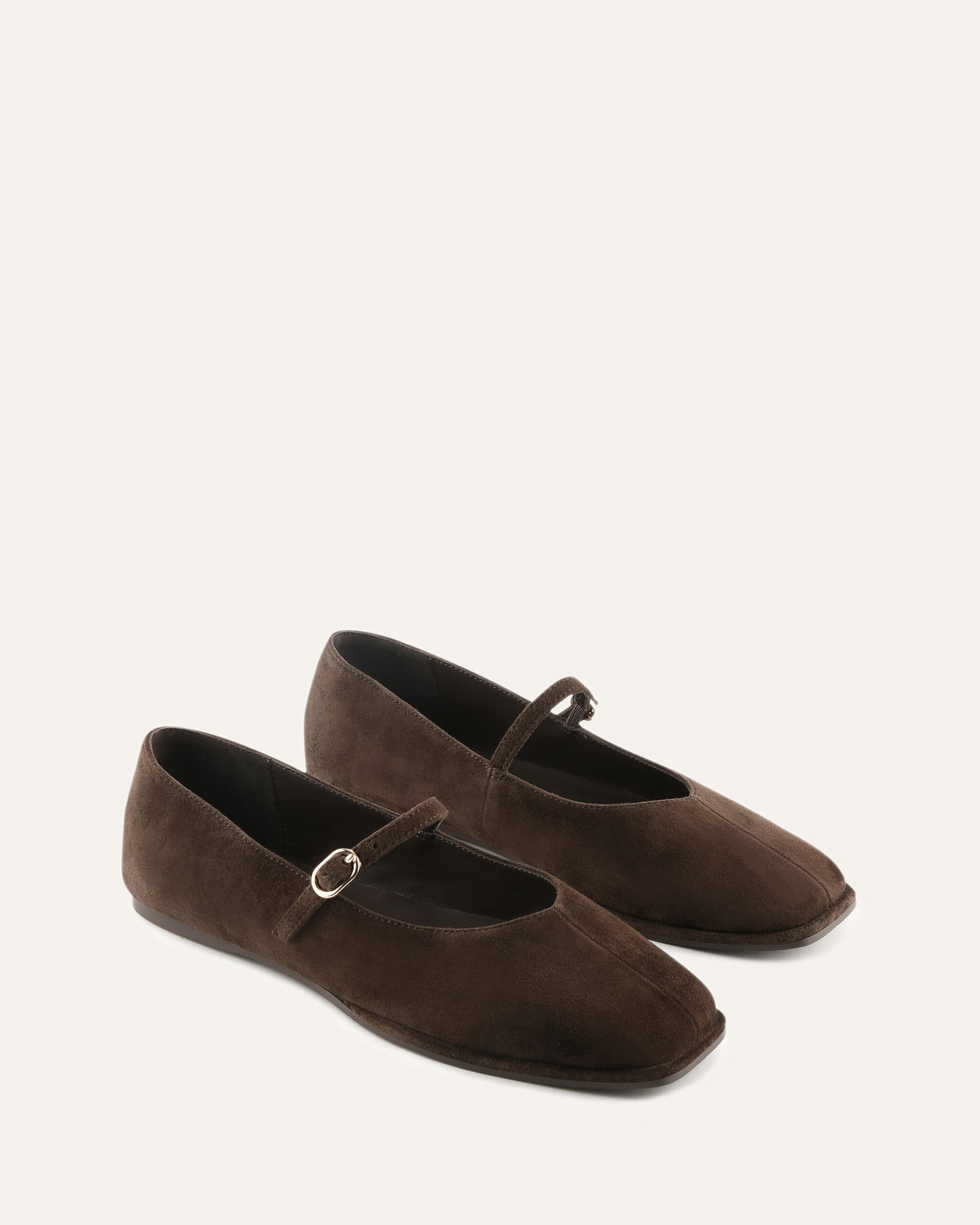 Brown flat shoe with a decorative bow on a light beige background