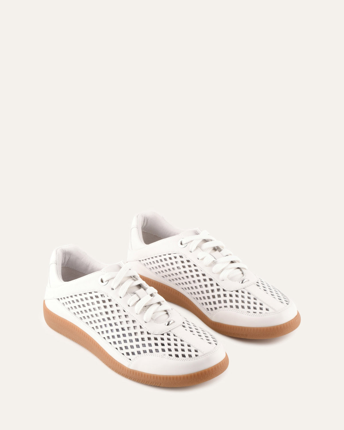 White sneakers with perforated design on a light gray background