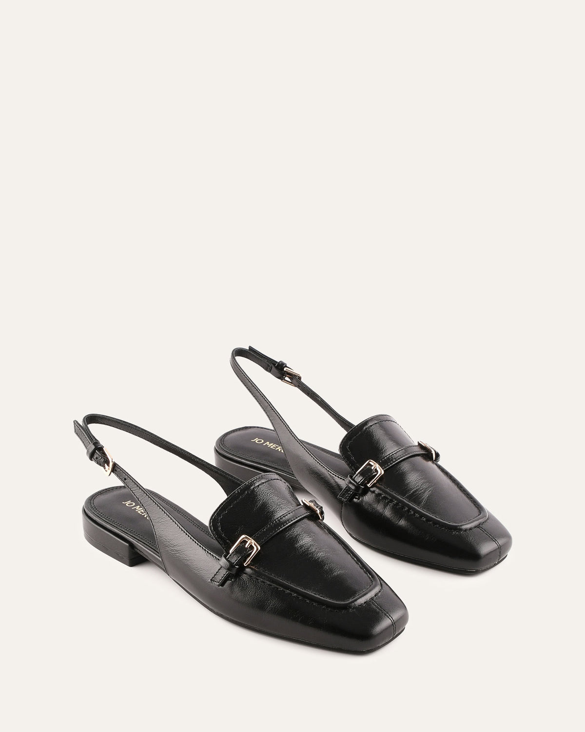Pair of black leather slingback shoes on a light gray background