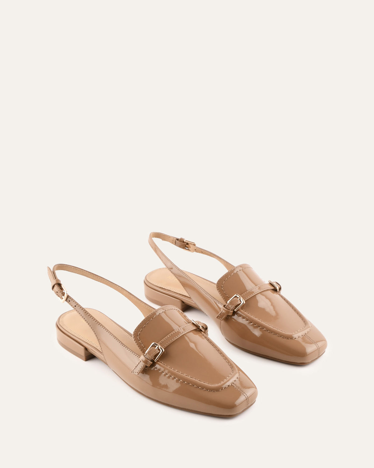 Pair of beige flat shoes with a slingback design on a white background